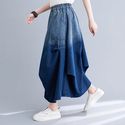 Gonna lunga in denim blu sfumato, design asimmetrico, tasca frontale, abbinata a scarpe bianche casual. Moda donna, abbigliamento trendy.