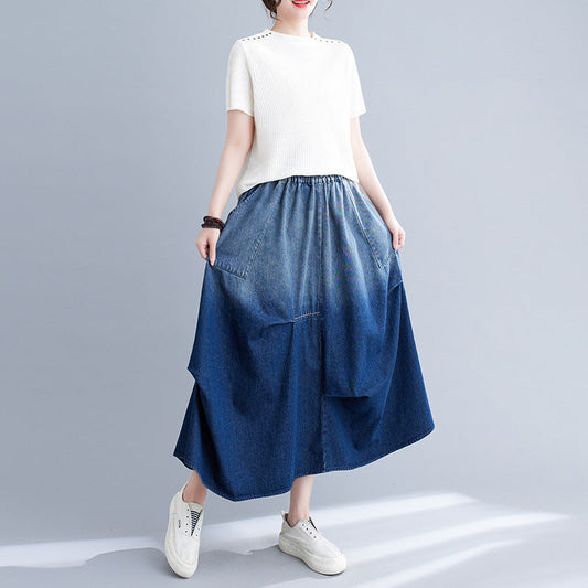 Donna con maglietta bianca e gonna lunga in denim blu, scarpe da ginnastica bianche. Moda casual femminile, abbigliamento estivo trendy.