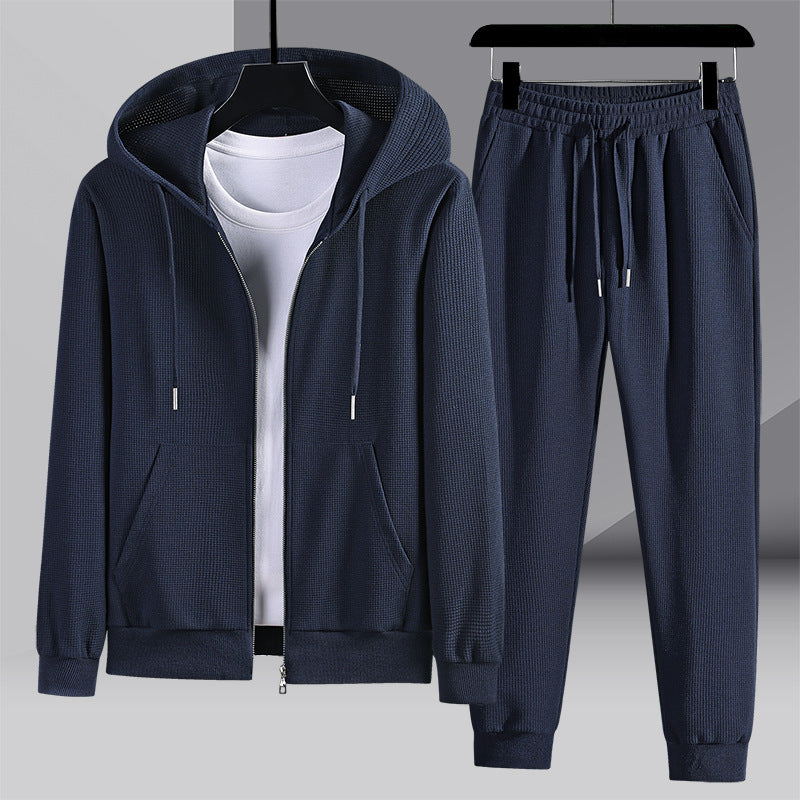 Tuta sportiva blu scuro con felpa con cappuccio e pantaloni, tessuto a coste, appesa su grucce. Abbigliamento casual uomo, moda autunno inverno.