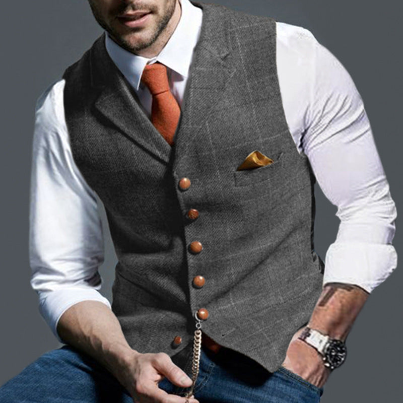 Uomo in gilet grigio elegante, camicia bianca e cravatta arancione, con orologio da polso e fazzoletto da taschino, moda maschile formale.