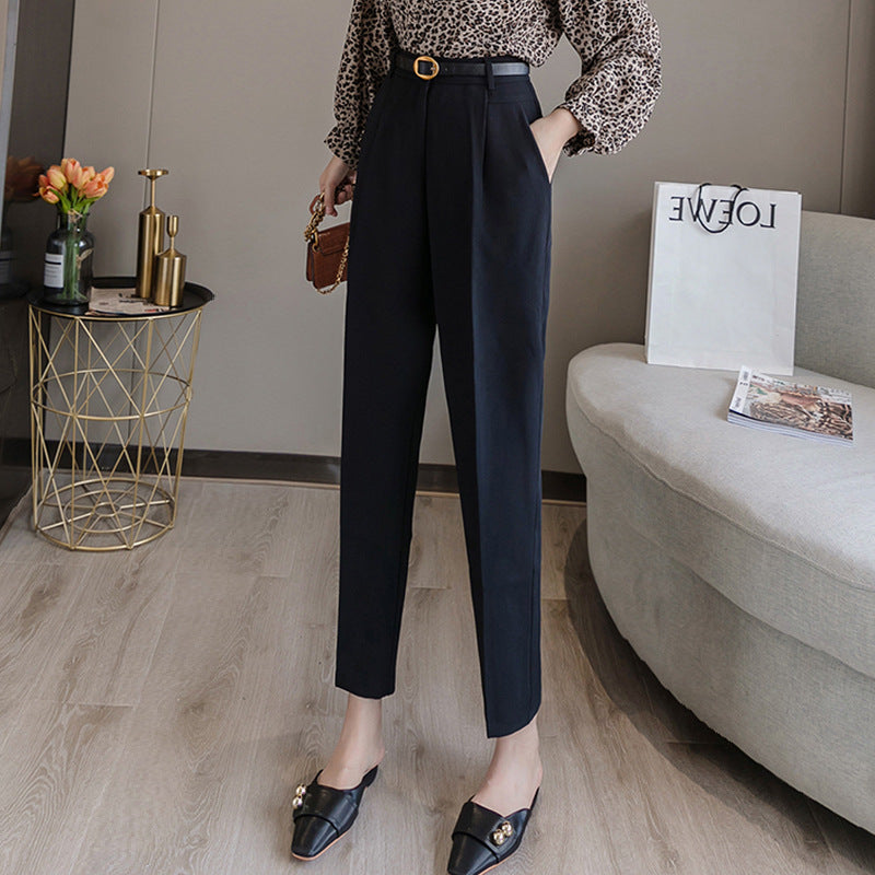 Pantaloni neri eleganti da donna con cintura, abbinati a una camicetta a fantasia leopardata. Moda femminile, abbigliamento casual chic.