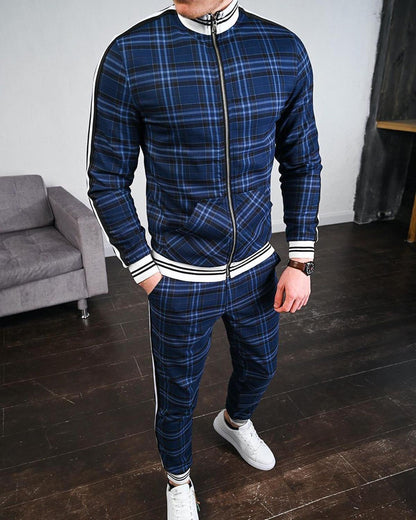 Uomo in tuta sportiva a quadri blu, con scarpe bianche, in piedi su pavimento in legno. Stile casual, moda maschile, abbigliamento moderno.