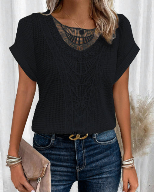 Donna con maglia nera traforata, jeans blu e cintura con fibbia dorata. Tiene una pochette beige. Stile casual chic, moda femminile elegante.