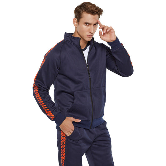 Uomo in tuta sportiva blu con dettagli arancioni, giacca con zip e pantaloni abbinati. Moda casual, abbigliamento sportivo maschile.