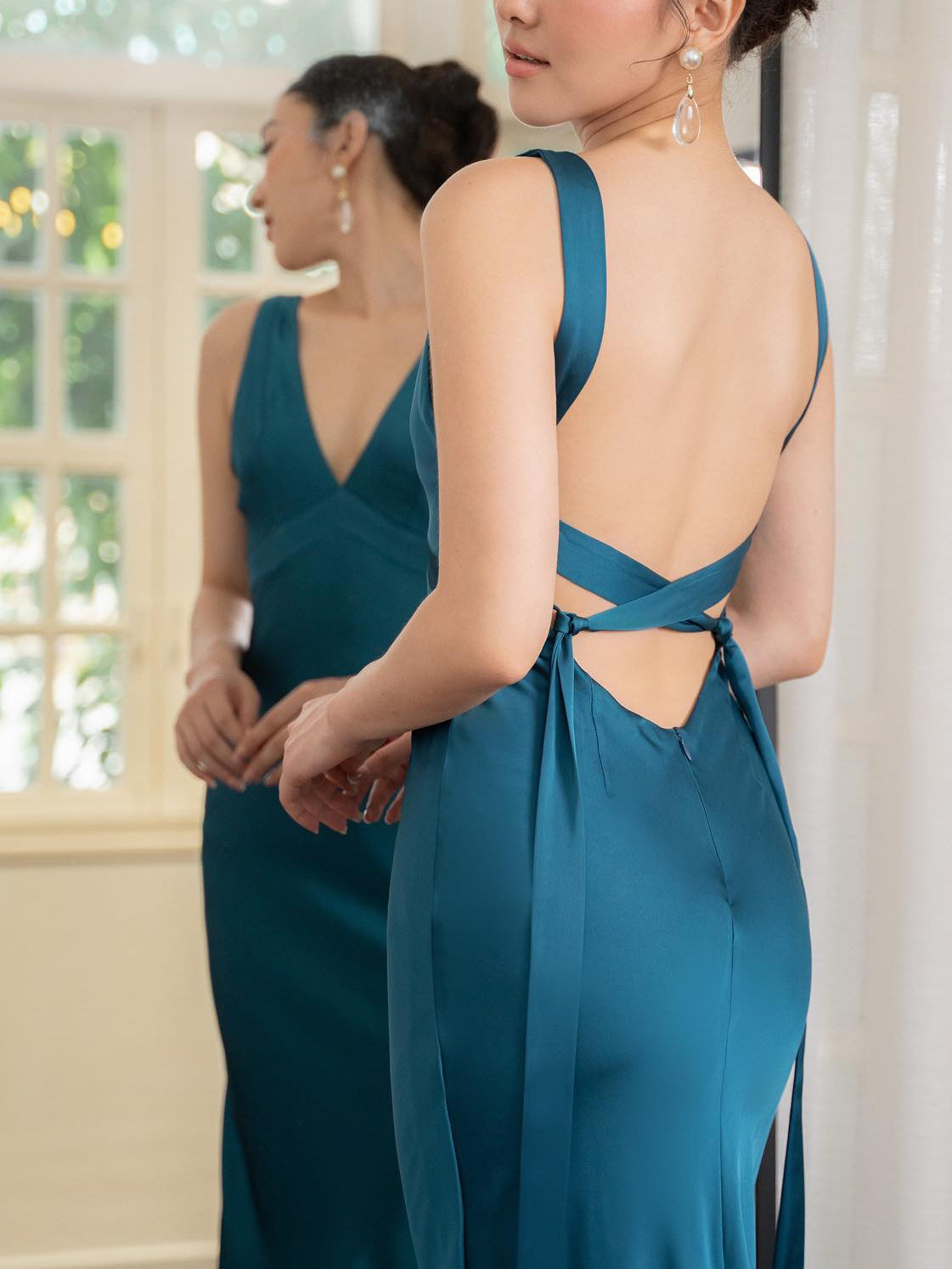 Donna in abito da sera blu con schiena scoperta, riflessa in uno specchio. Eleganza, moda femminile, abbigliamento da cerimonia.