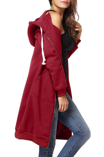 Donna con cappotto lungo rosso, cappuccio e tasche, indossa jeans e top nero. Moda casual autunnale, abbigliamento femminile trendy.