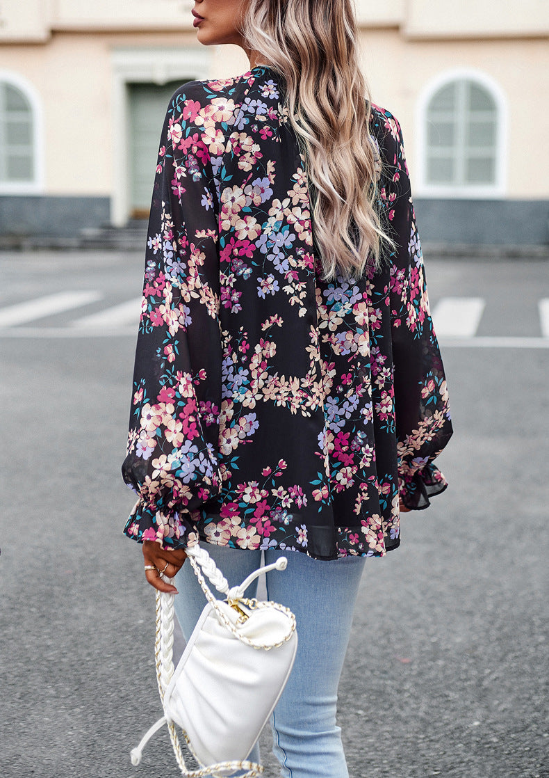 Donna con camicetta floreale nera, jeans chiari e borsa bianca a tracolla. Moda casual femminile, look primaverile, abbigliamento trendy.