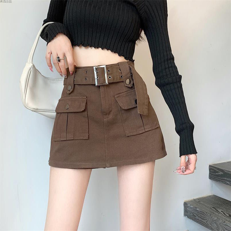 Donna con gonna marrone a vita alta con tasche e cintura, maglione nero a coste, borsa bianca. Moda autunnale casual, stile urbano.
