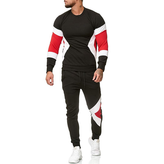 Tuta sportiva uomo nera con dettagli rossi e bianchi, design moderno, maniche lunghe, pantaloni abbinati, scarpe bianche. Moda casual maschile.