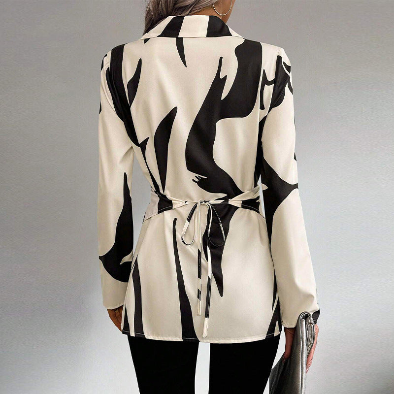 Giacca donna elegante bianca e nera con motivo astratto, cintura posteriore, abbinata a pantaloni neri. Moda femminile, abbigliamento formale.