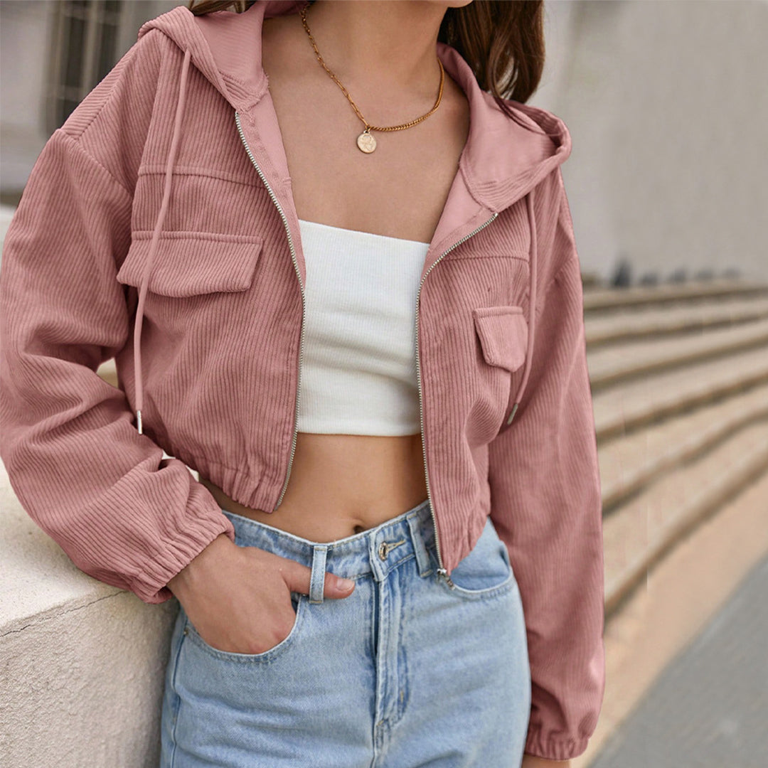 Giacca corta rosa in velluto a coste, indossata con top bianco e jeans a vita alta. Moda casual femminile, stile urbano trendy.