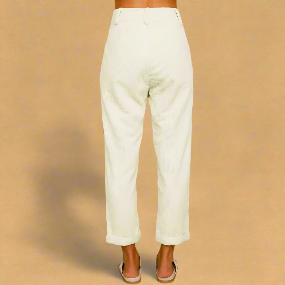 Pantaloni bianchi a vita alta in tessuto leggero, indossati da una persona di spalle su sfondo beige. Stile casual, moda estiva, abbigliamento donna.
