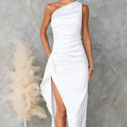 Abito da sera bianco monospalla con spacco laterale, elegante e moderno, su sfondo grigio. Perfetto per eventi formali e cerimonie.