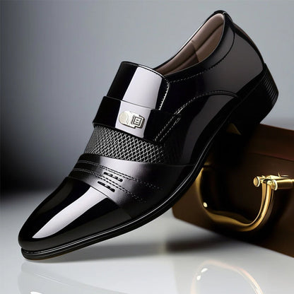 Scarpa elegante da uomo in pelle nera lucida con dettagli traforati e fibbia metallica, posata su una superficie riflettente accanto a una valigetta.