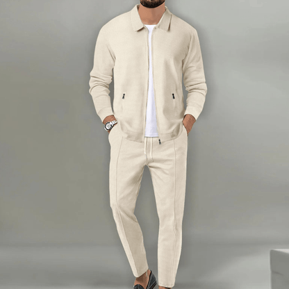 Uomo in abito casual beige, giacca e pantaloni coordinati, indossa mocassini neri e orologio. Moda maschile elegante e moderna.