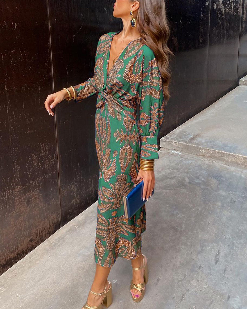 Donna con abito lungo verde a fantasia, sandali dorati e pochette blu. Moda elegante, stile autunnale, abbigliamento femminile chic.