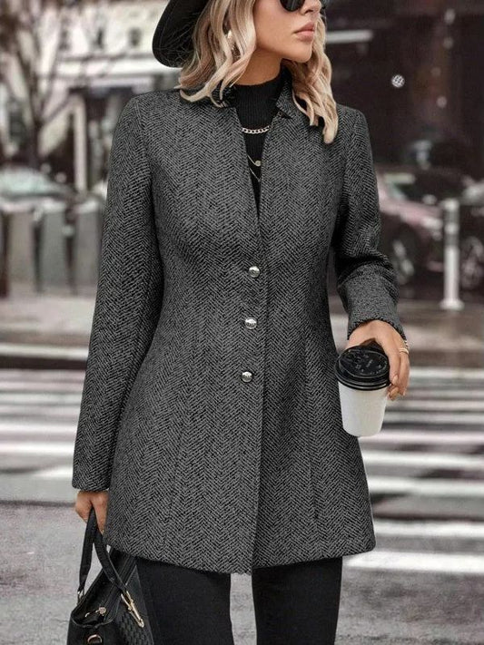 Donna con cappotto grigio elegante, cappello nero e occhiali da sole, tiene caffè da asporto e borsa. Moda autunnale in città.