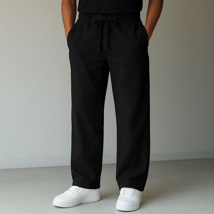 Pantaloni neri larghi con coulisse, indossati con scarpe da ginnastica bianche. Moda casual uomo, abbigliamento comodo e moderno.