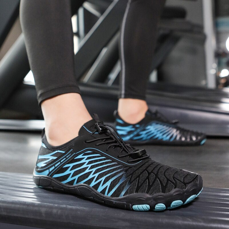 Scarpe da corsa minimaliste nere e blu su tapis roulant, design leggero e traspirante, ideali per allenamenti fitness e corsa indoor.