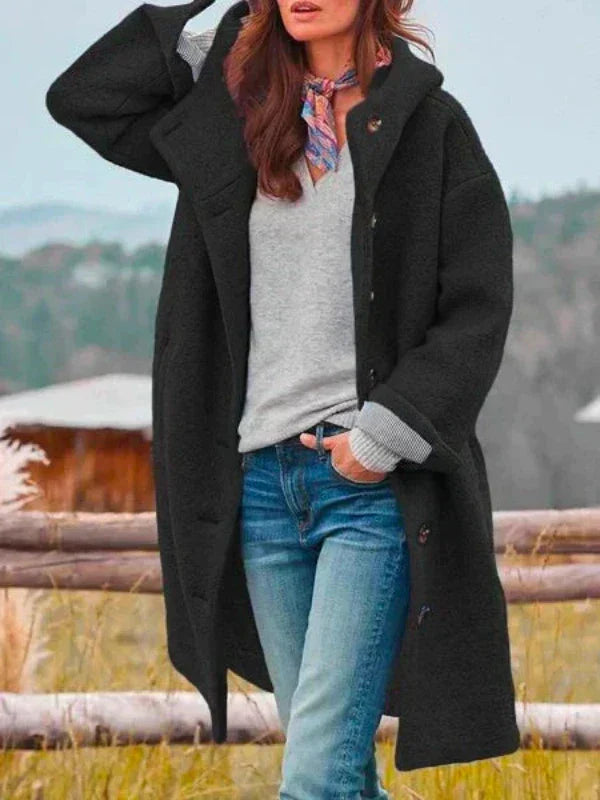 Donna con cappotto nero invernale, jeans e sciarpa colorata, posa all'aperto. Moda autunnale, abbigliamento casual, stile elegante.