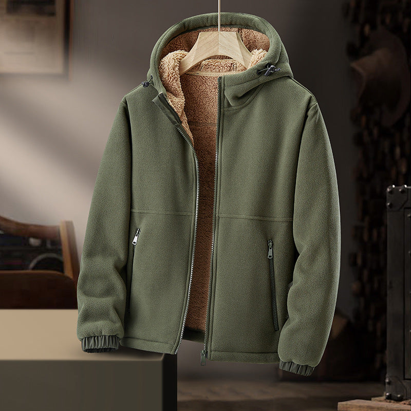 Giacca invernale verde con cappuccio, fodera in pile marrone, chiusura a zip, tasche laterali, appesa su appendiabiti in ambiente interno.