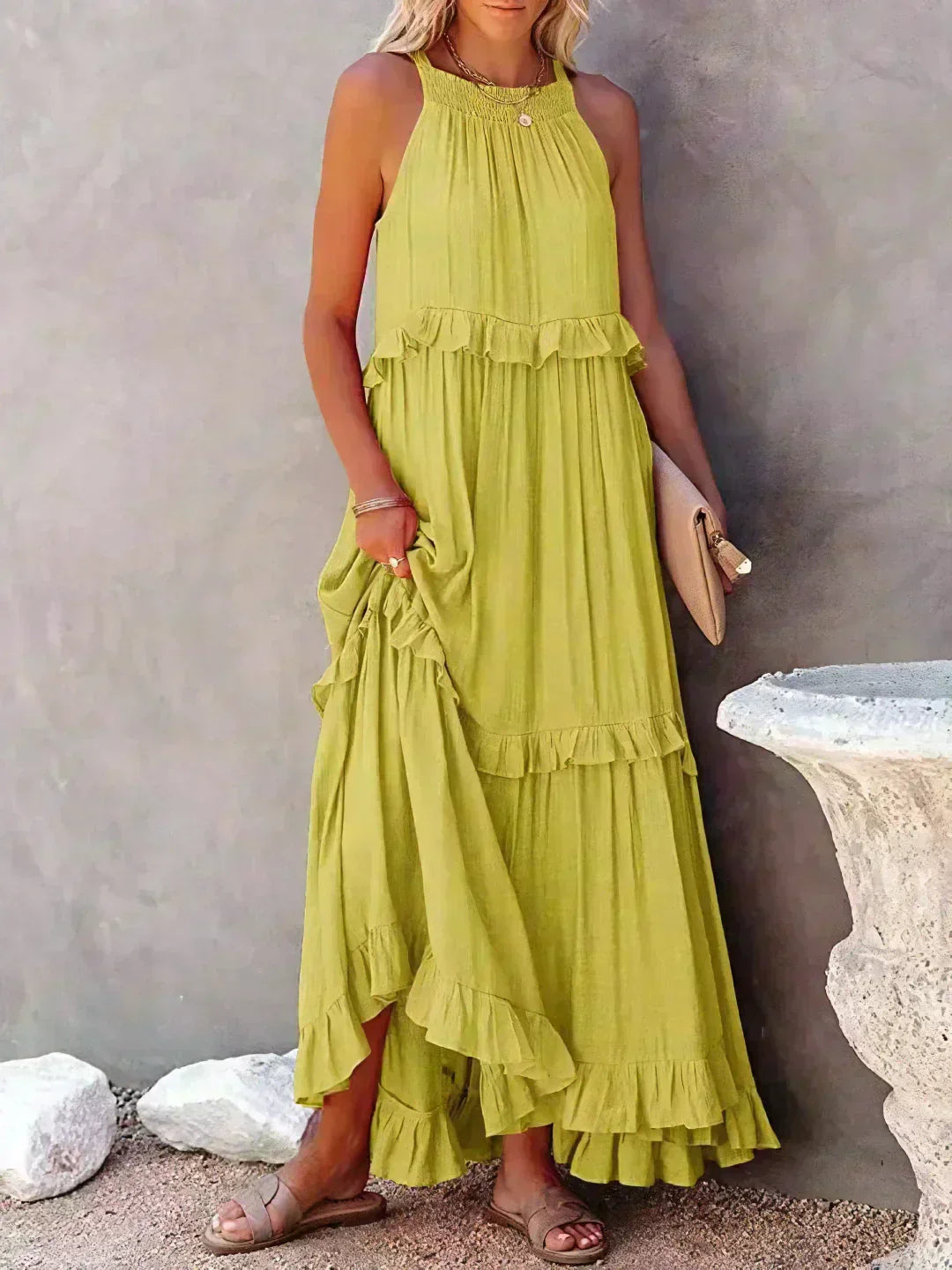 Donna con abito lungo verde lime, senza maniche, con balze, sandali beige e pochette. Moda estiva elegante, abbigliamento casual chic.