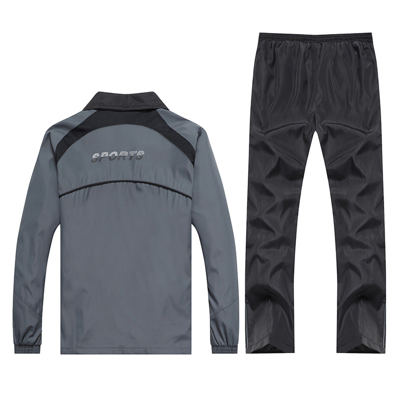 Tuta sportiva grigia e nera, giacca con scritta "SPORTS" sul retro, pantaloni coordinati. Abbigliamento atletico, moda fitness uomo.
