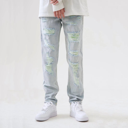 Jeans strappati uomo, colore chiaro, stile casual, abbinati a scarpe da ginnastica bianche. Moda streetwear, tendenze abbigliamento maschile.