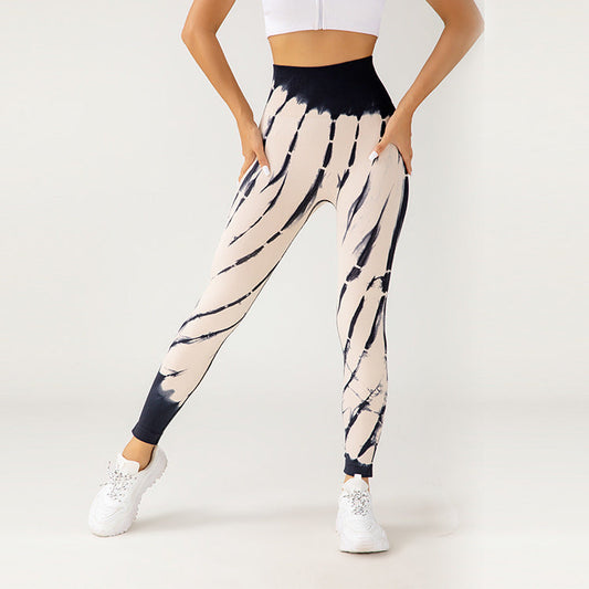 Leggings a vita alta con motivo tie-dye nero e bianco, abbinati a top bianco e scarpe da ginnastica. Stile moda fitness donna.
