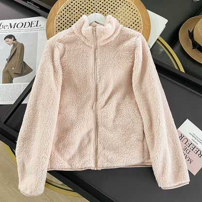 Giacca in pile rosa chiaro su tavolo nero, con zip frontale. Moda autunnale, abbigliamento caldo e morbido. Sfondo con rivista e cappello.