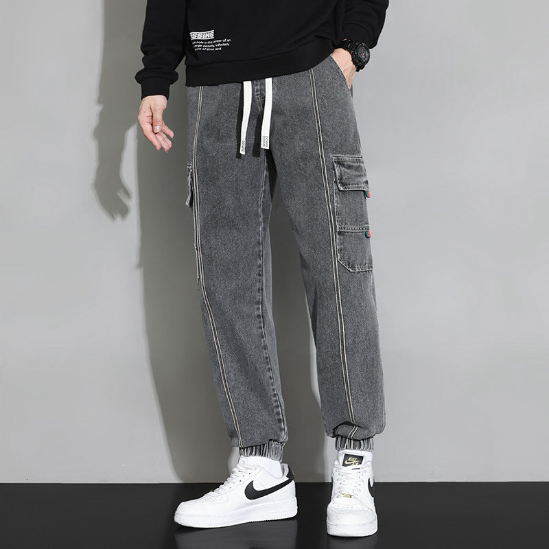 Pantaloni cargo grigi da uomo con tasche laterali, indossati con sneakers bianche Nike. Stile casual moderno, moda streetwear maschile.