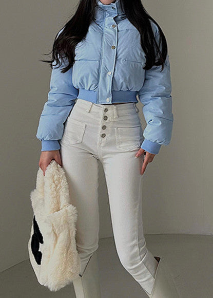 Giacca invernale azzurra abbinata a pantaloni bianchi a vita alta, borsa in pelliccia sintetica. Moda donna, abbigliamento casual chic.