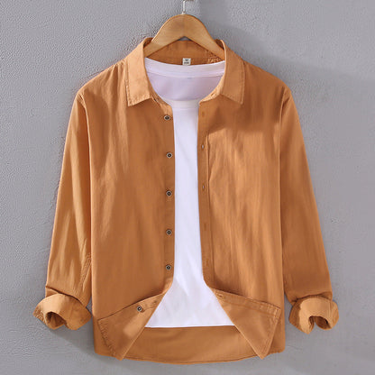 Camicia casual marrone chiaro da uomo su gruccia, con maniche lunghe e bottoni, sopra una maglietta bianca. Moda maschile, abbigliamento casual.