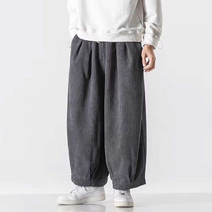 Pantaloni larghi a righe grigie, stile casual, indossati con felpa bianca e scarpe da ginnastica bianche. Moda uomo, abbigliamento streetwear.