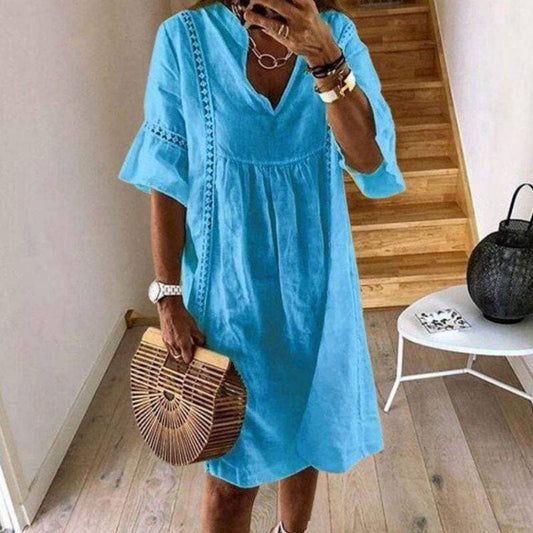 Donna con abito estivo azzurro, maniche a volant, borsa in legno, in piedi su pavimento in legno chiaro. Moda casual, stile estivo elegante.