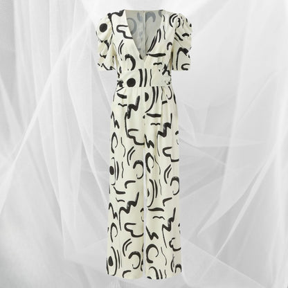 Abito lungo bianco con motivo astratto nero, scollo a V profondo e maniche corte a sbuffo, su sfondo di tulle bianco. Moda elegante e moderna.