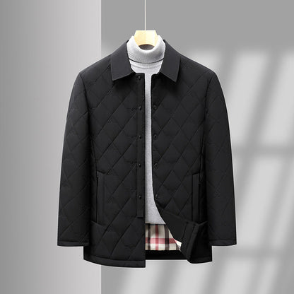 Giacca trapuntata nera elegante appesa, con colletto classico e tasche, su sfondo grigio. Moda uomo, abbigliamento invernale, stile casual chic.