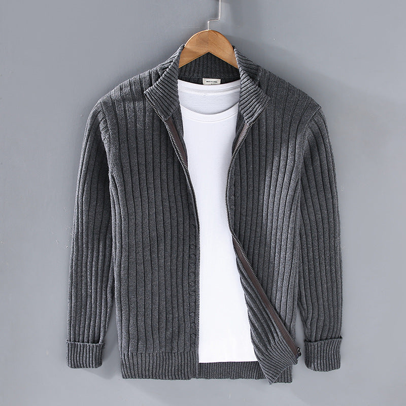 Cardigan grigio a coste su gruccia, con zip aperta e maglietta bianca sotto. Moda uomo, abbigliamento casual, stile autunnale.