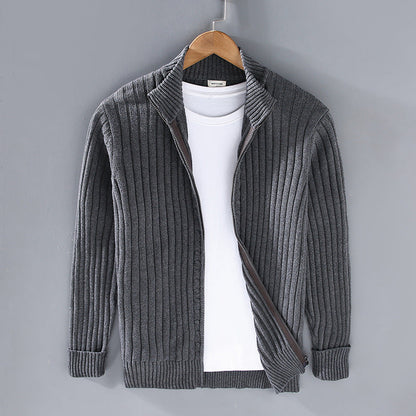 Cardigan grigio a coste su gruccia, con zip aperta e maglietta bianca sotto. Moda uomo, abbigliamento casual, stile autunnale.