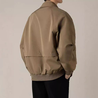 Giacca bomber beige da uomo, stile casual, tessuto liscio, maniche lunghe, indossata con pantaloni neri. Moda maschile autunnale elegante.
