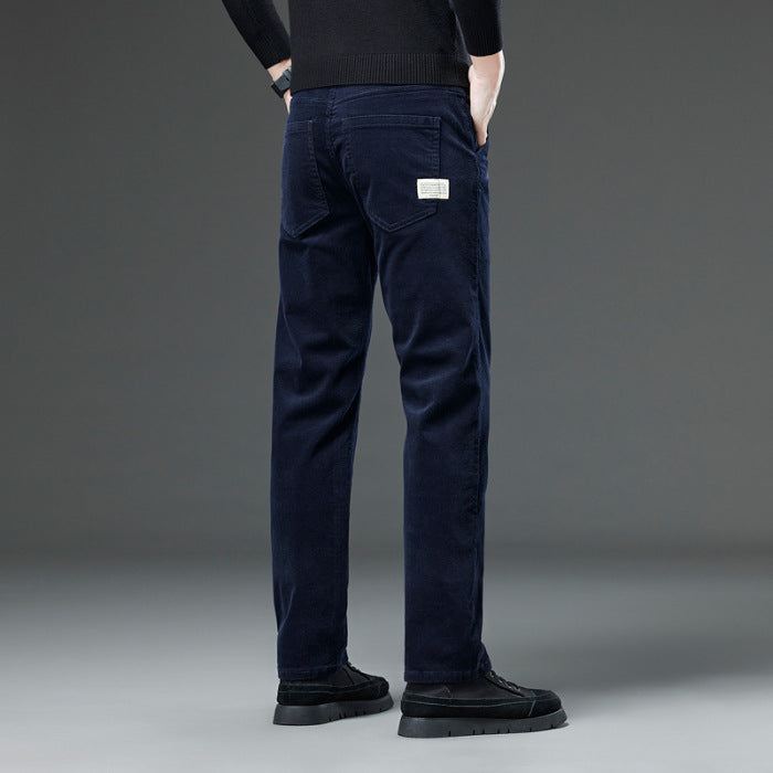 Jeans uomo blu scuro, vestibilità slim, tasche posteriori, etichetta bianca, indossati con maglione nero e scarpe nere su sfondo grigio.