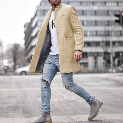 Uomo con cappotto beige elegante, jeans strappati e stivali grigi cammina in città. Moda maschile urbana, stile casual chic.