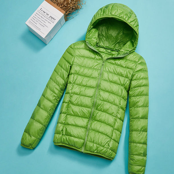 Giacca verde con cappuccio su sfondo azzurro, design trapuntato, leggera e impermeabile. Ideale per moda autunnale e invernale.
