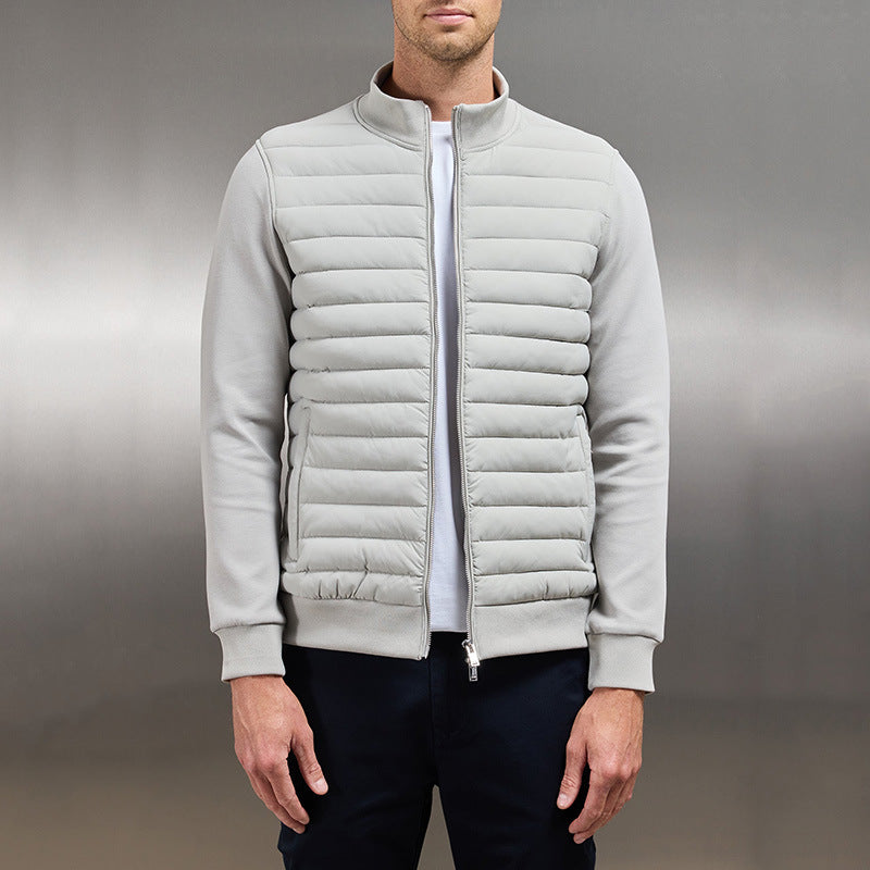 Giacca bomber uomo grigia, imbottita, con zip frontale, indossata su maglietta bianca e pantaloni scuri. Stile casual elegante.