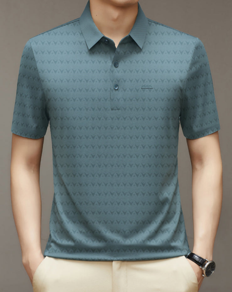 Camicia polo uomo verde con motivo geometrico, maniche corte, colletto classico e bottoni, indossata con pantaloni beige. Moda casual elegante.