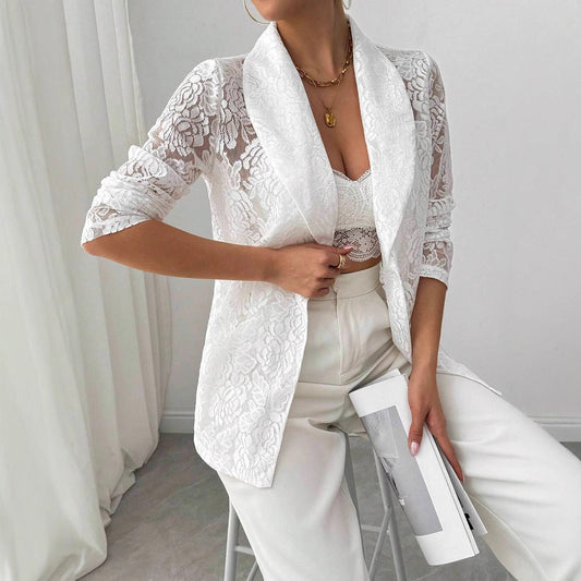 Donna in elegante completo bianco in pizzo, giacca e top coordinati, pantaloni a vita alta, accessori dorati, moda femminile chic e sofisticata.