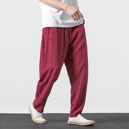 Uomo con pantaloni larghi rossi in lino, cammina su sfondo bianco. Moda casual maschile, abbigliamento estivo, stile rilassato.
