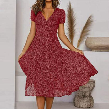 Donna con abito rosso a fiori, maniche corte, in posa elegante. Moda femminile estiva, stile casual chic. Sfondo neutro con decorazioni naturali.