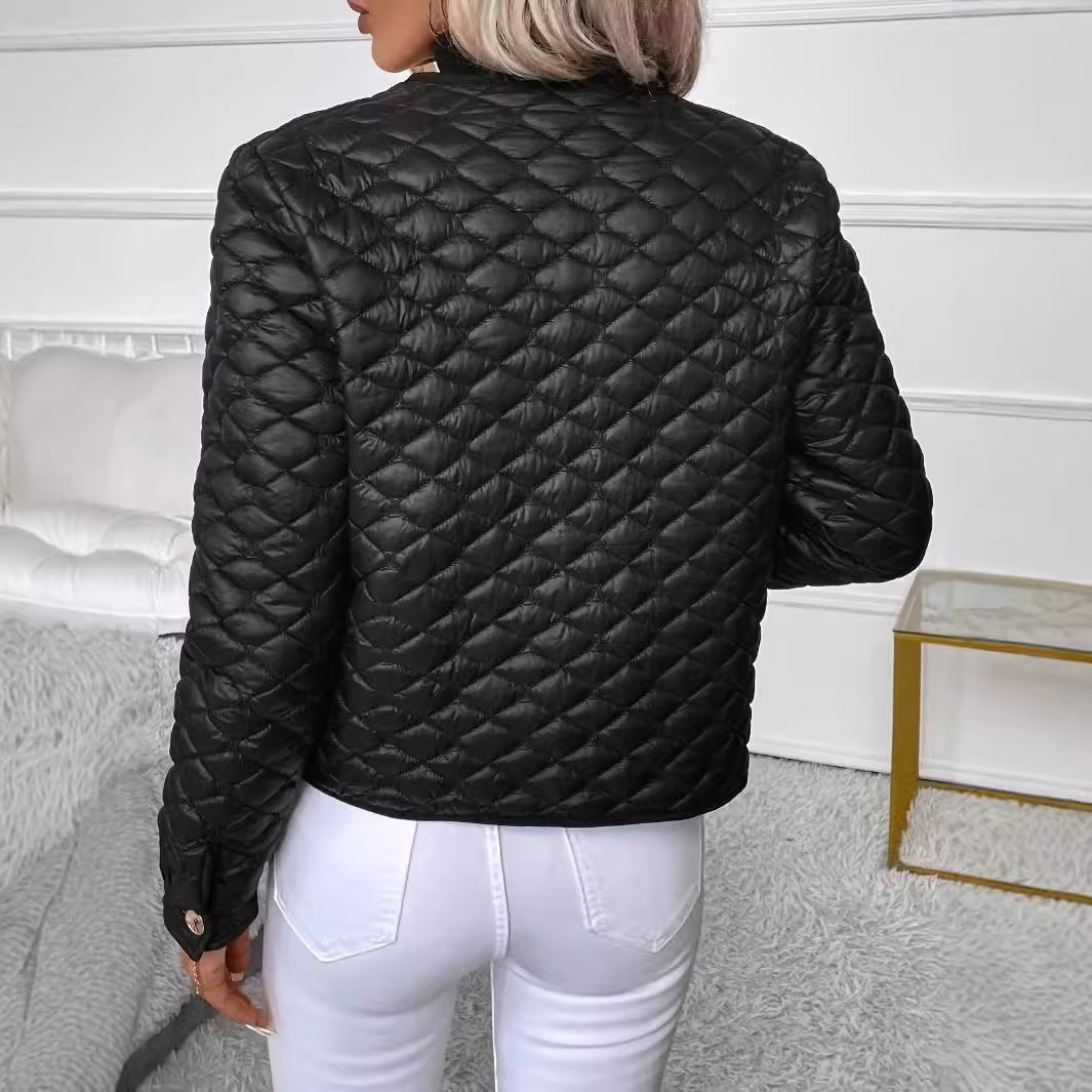Giacca trapuntata nera da donna, vista posteriore, abbinata a pantaloni bianchi. Design elegante e moderno, ideale per moda autunnale.