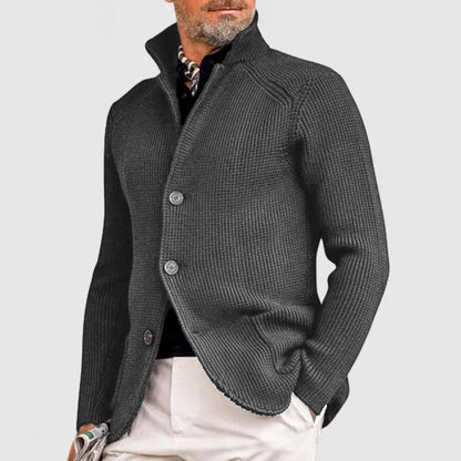 Giacca uomo elegante in maglia grigia, abbottonata, con colletto rialzato. Moda maschile autunno-inverno, stile casual chic.